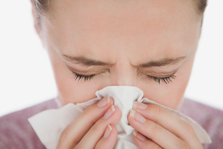 A woman sneezing into a tissue