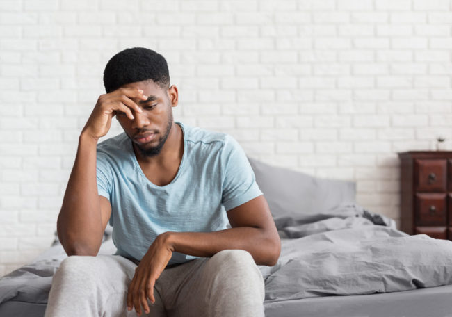 A man feeling sad while sitting on a bed