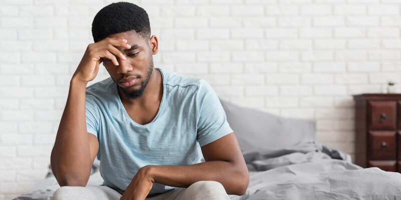 A man feeling sad while sitting on a bed