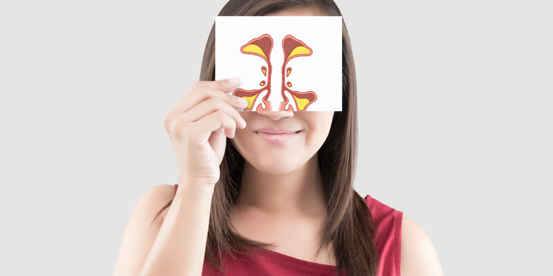 Smiling woman holding a picture of a sinus to her face