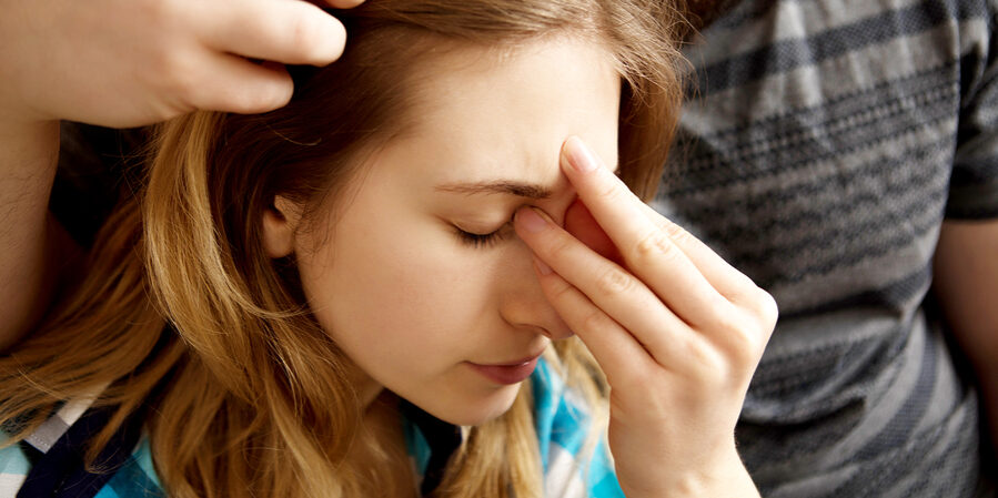 Young woman sitting on sofa with sinus pain, her partner is carring on her.