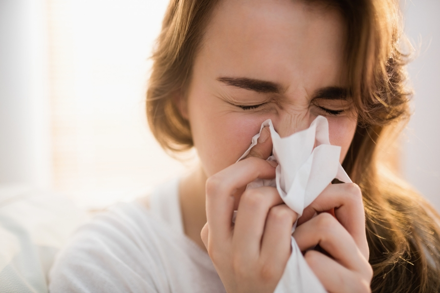 A woman with nasal congestion blowing her nose