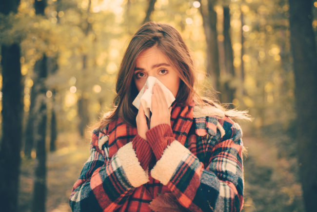 A young woman blowing her nose while outside