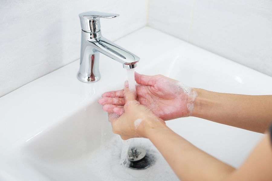 Woman washing her hands in a white sink