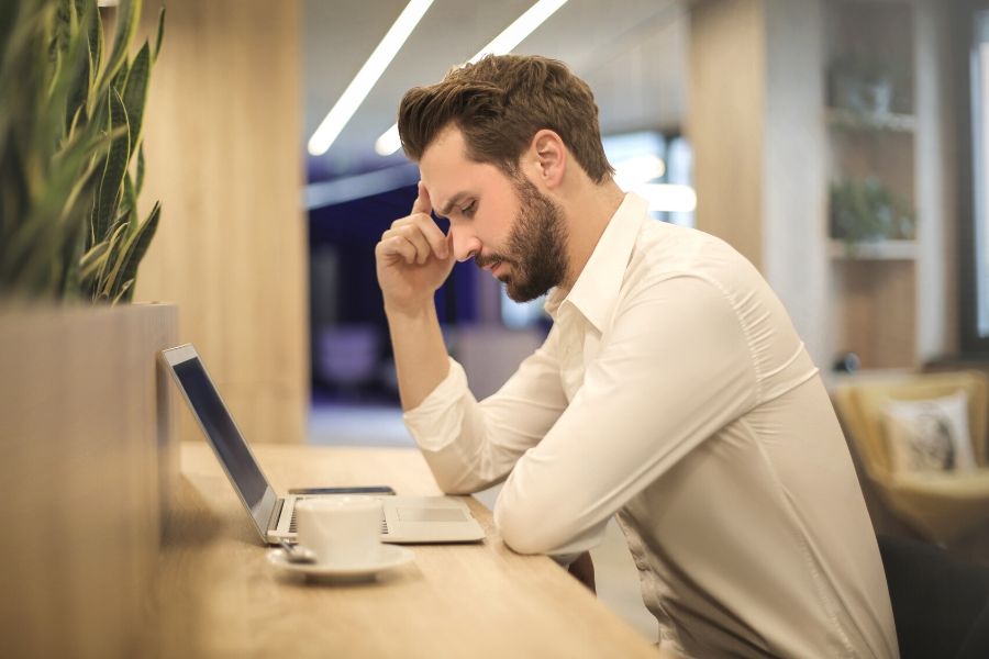 Man in library looking at computer dealing with sinus pressure